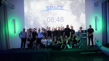 Group posing on stage with space theme.