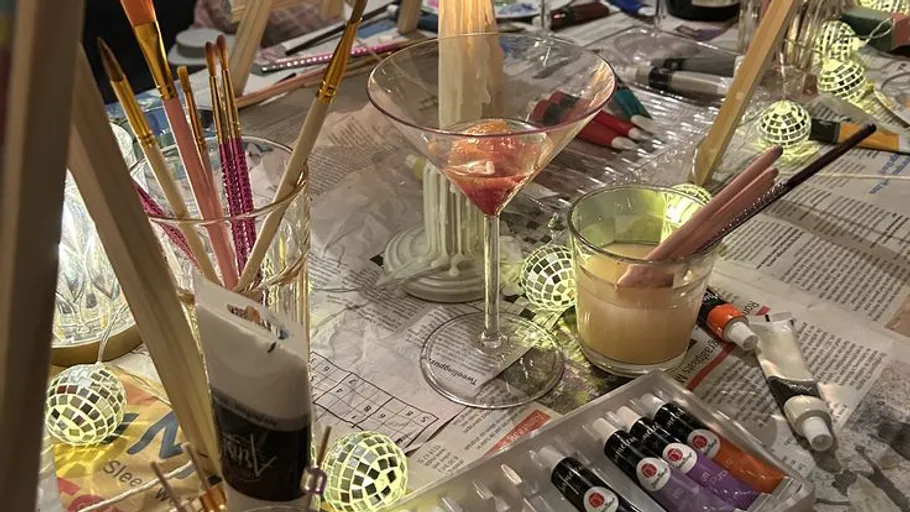 Art supplies and cocktail on a table.