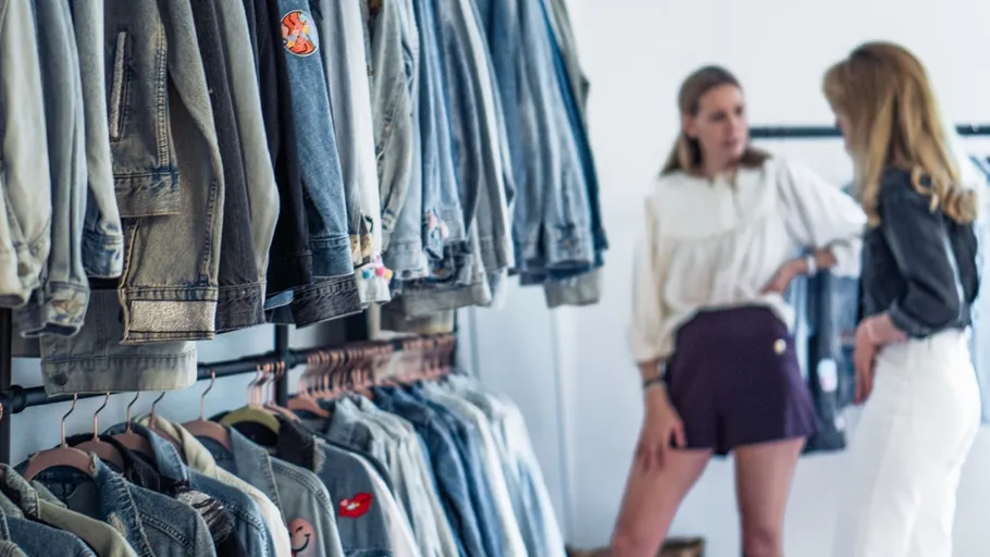 Hanging denim jackets, two women talking nearby.