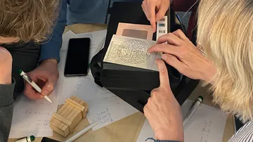 Hände lösen Labyrinth-Rätsel auf Schreibtisch.