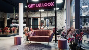 Modern salon lounge with pink furniture, neon sign.