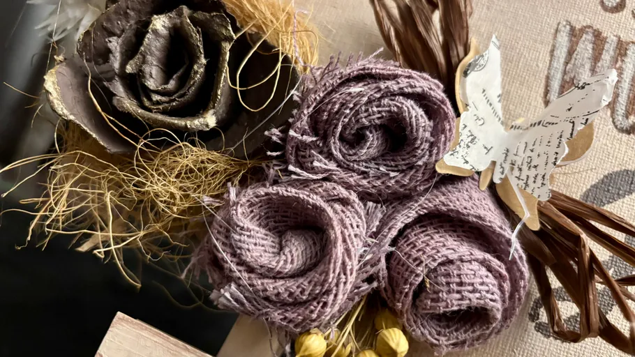 Fabric flowers and paper butterfly on canvas.