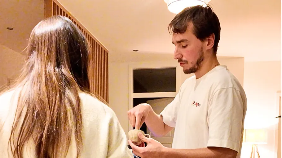 Man eating with woman in a kitchen.