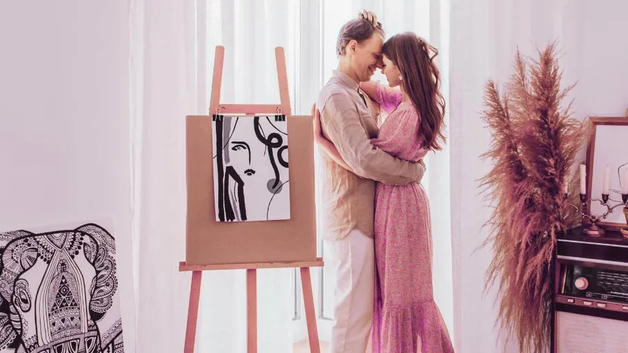 Paar umarmt sich in künstlerischem Raum mit Staffelei.