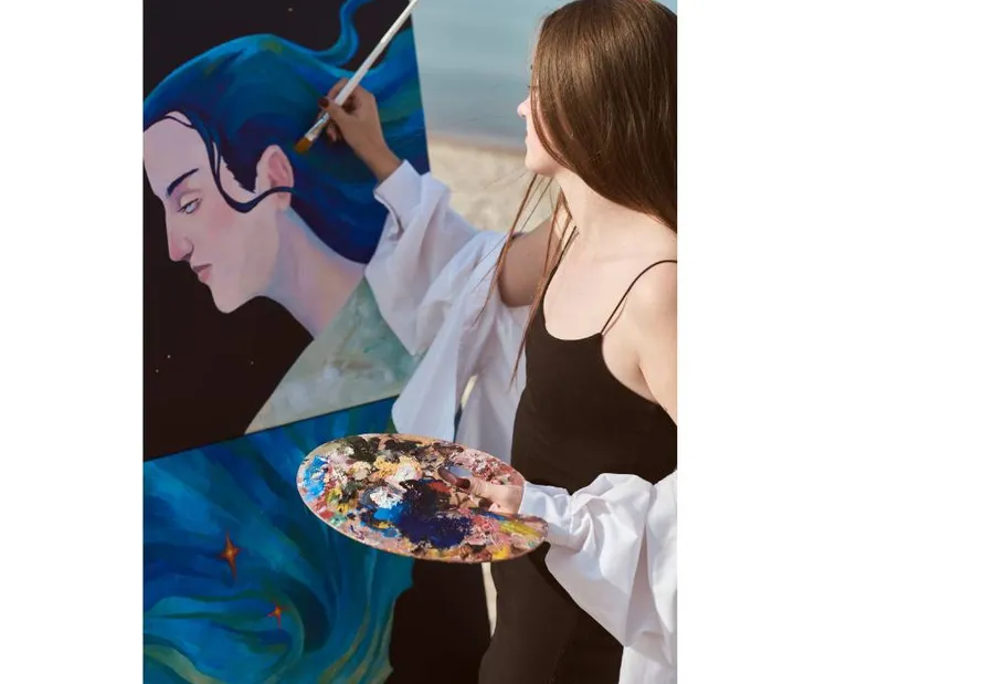 Woman painting portrait at beachfront.