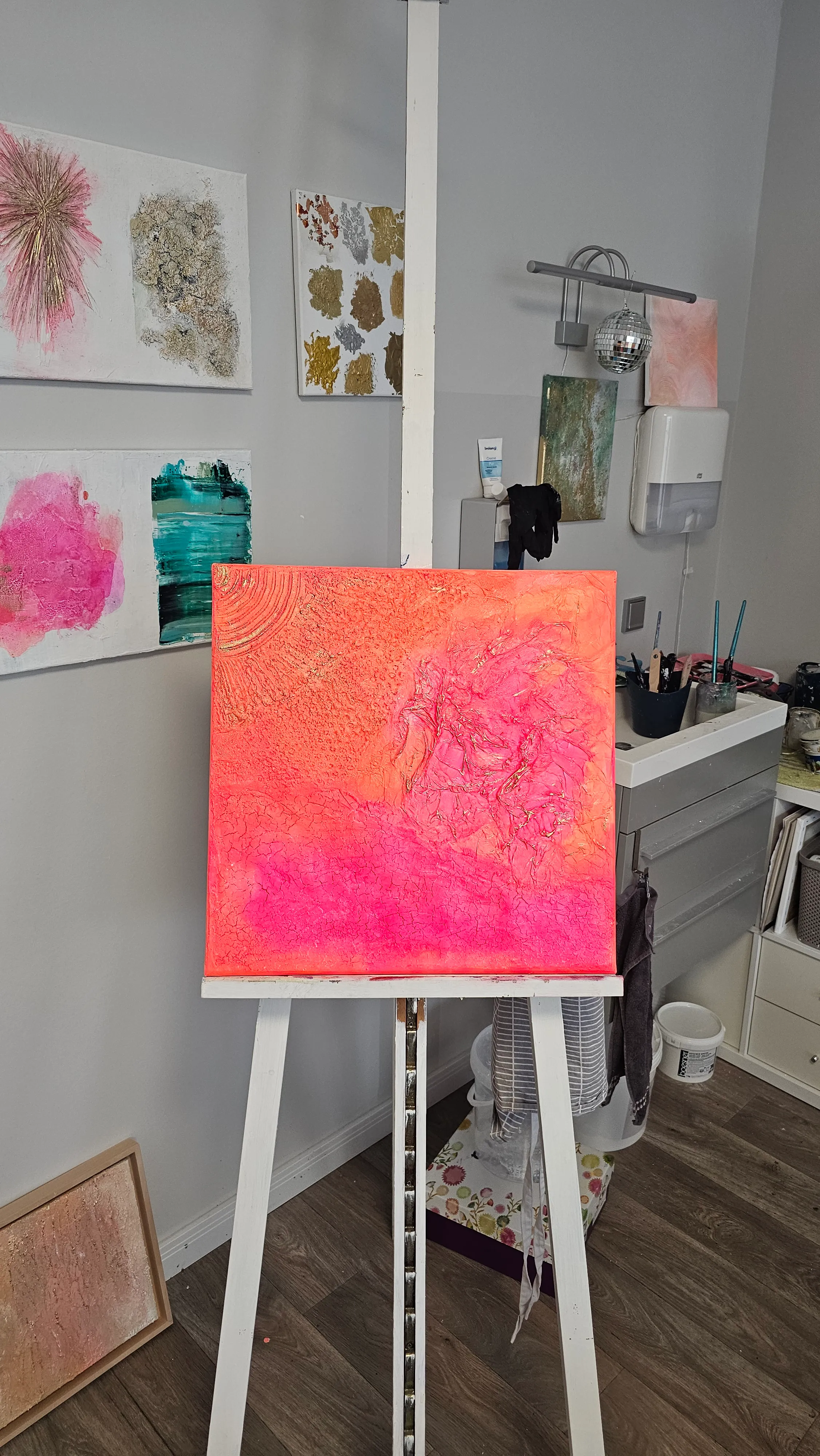 Abstract pink-orange painting on easel in studio.