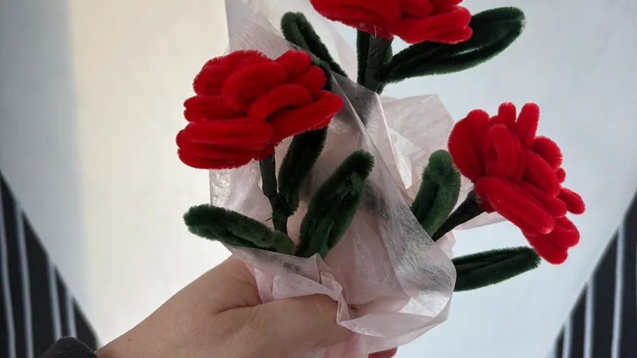 Hand hält Strauß roter Filzblumen.
