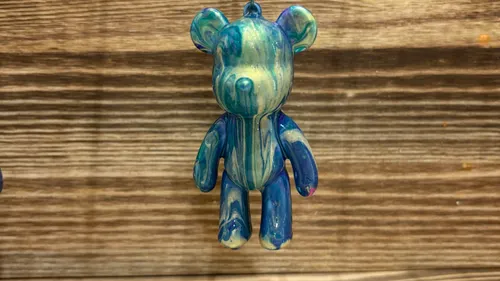 Bemalte Bärenfigur an Holzwand hängend.