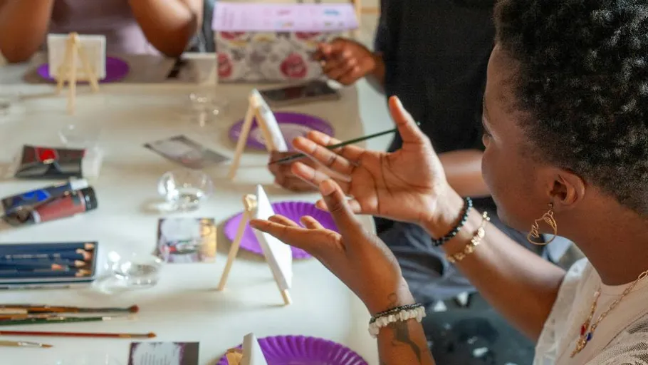 Person painting at table with others.