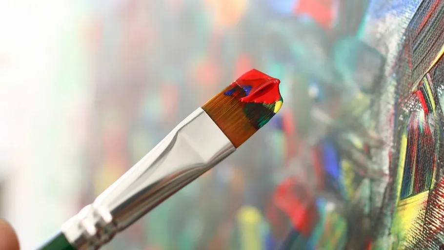 Pinsel mit roter Farbe nahe bunter Leinwand.