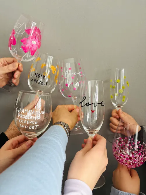 Hands holding decorated wine glasses in celebration.