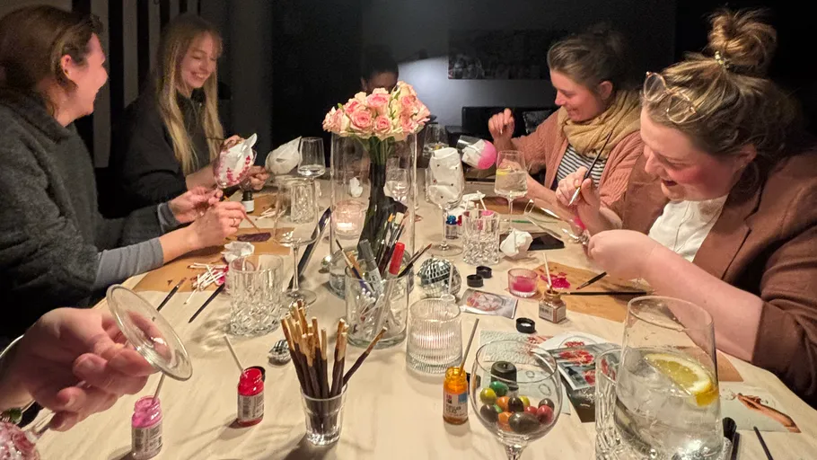 Group painting eggs around a dining table.