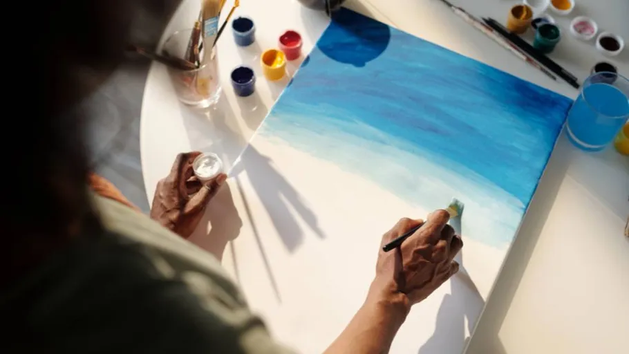 Person painting blue gradient on canvas.