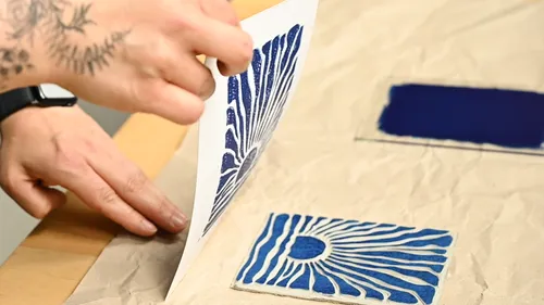 Person hebt Papier von blauem Druckblock.