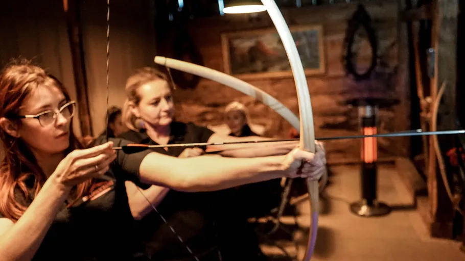 Two women practicing archery indoors.