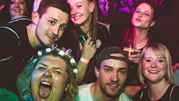 Gruppe von Freunden lächelt auf einer Party.