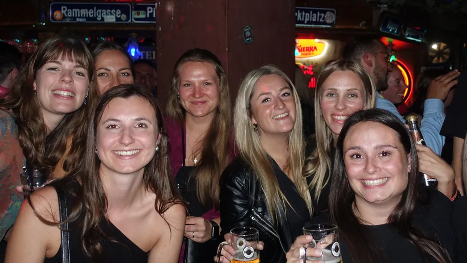 Lächelnde Frauengruppe hält Getränke drinnen.