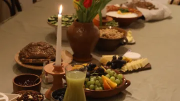 Tisch mit Kerze, Obst und Speisen.
