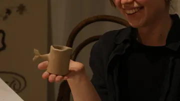 Person hält einen walförmigen Keramikbecher.