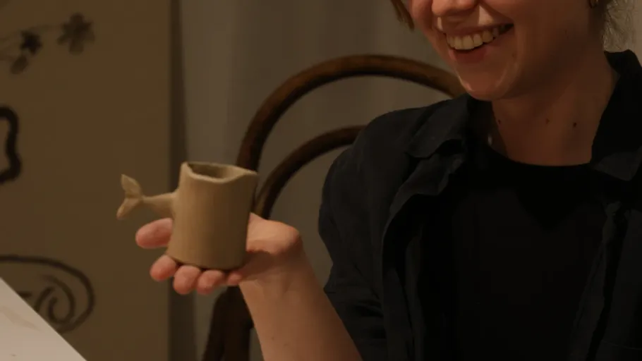 Person hält einen walförmigen Keramikbecher.