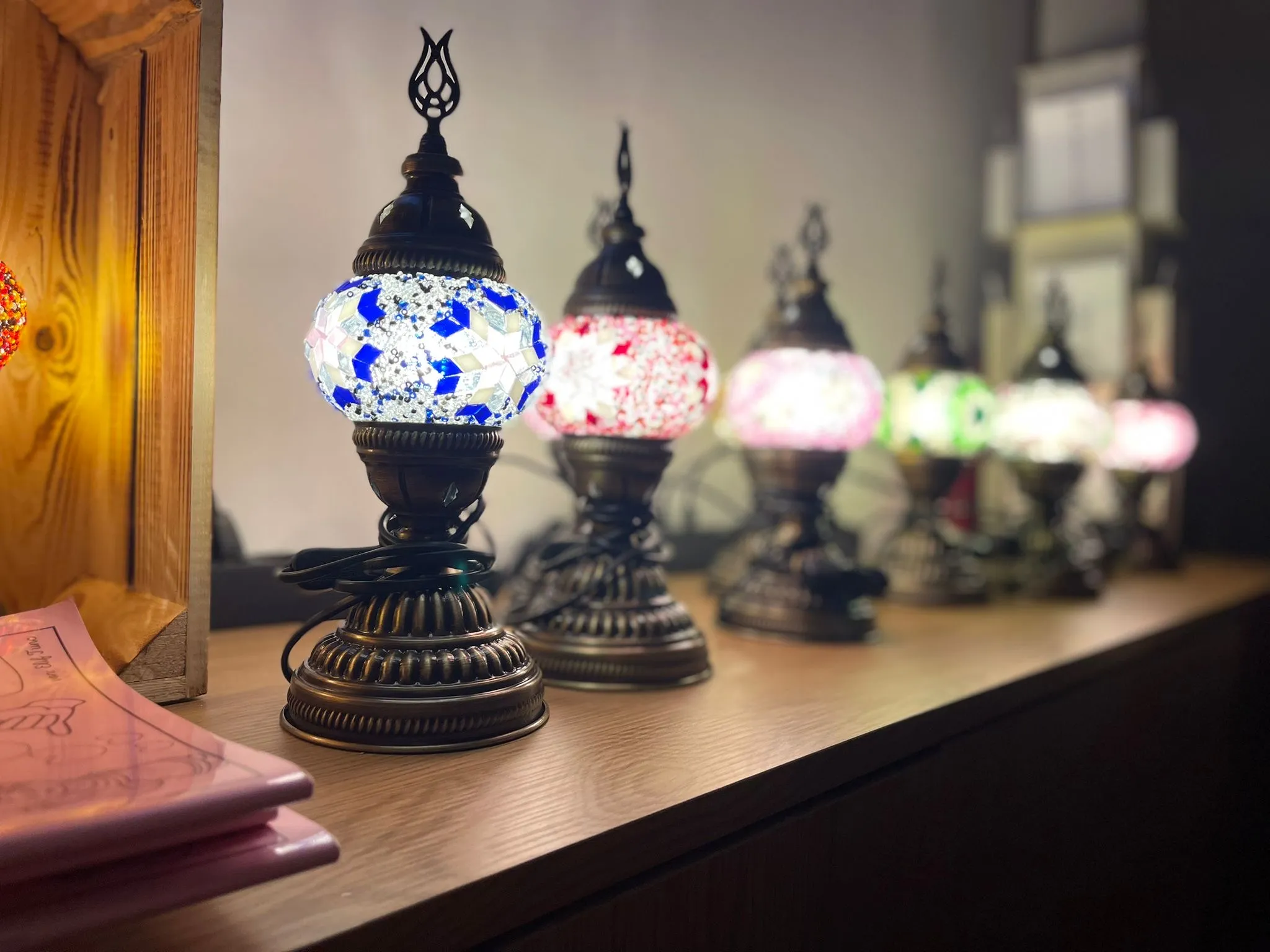 Bunte Mosaiklampen auf einer Holzoberfläche.