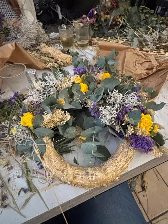 Blumenkranz mit bunten Blumen auf Tisch.