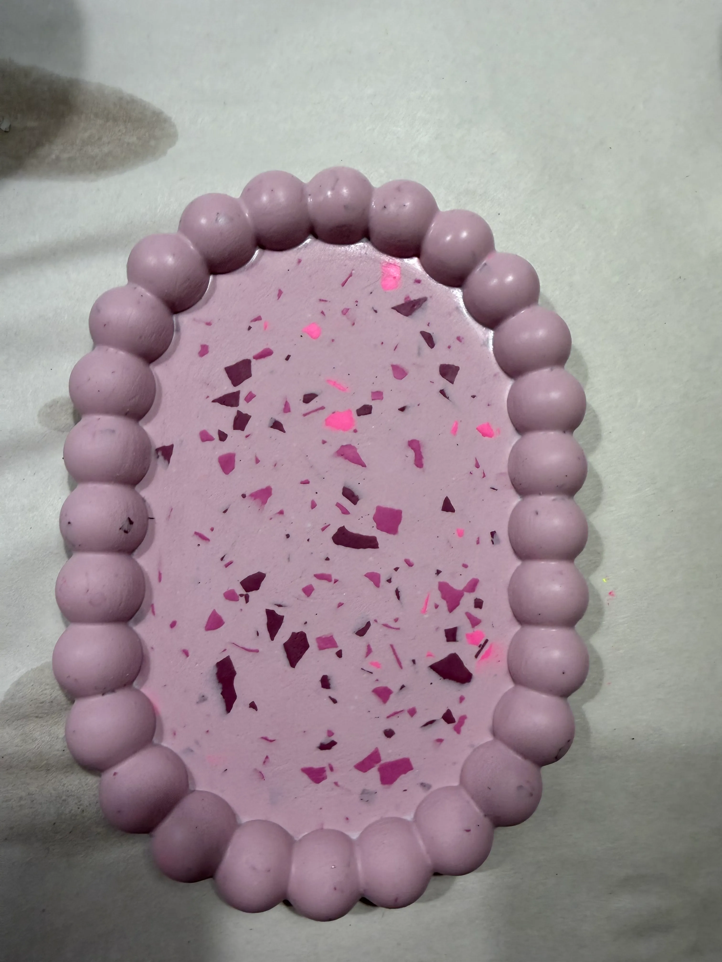 Rosa Tablett mit dekorativem Rand auf Tisch.