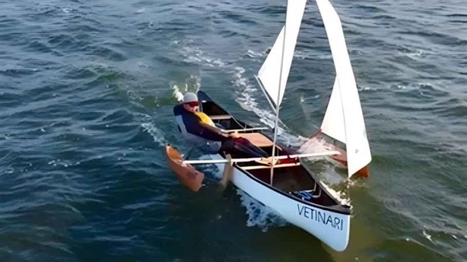 Man sails small boat on open water.