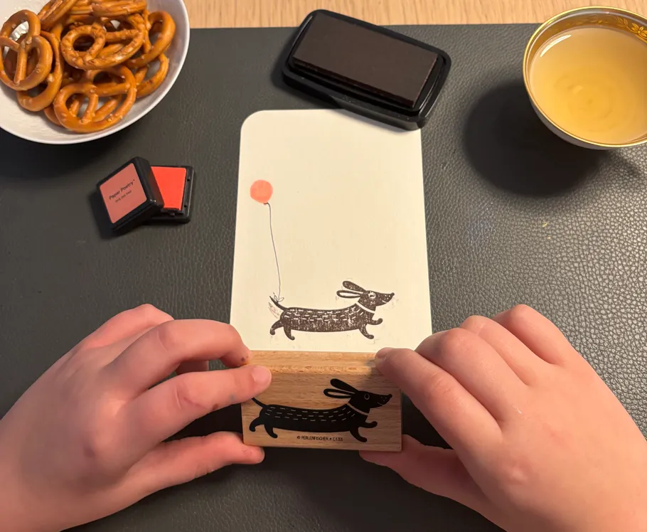 Hands stamping running dog with balloon.