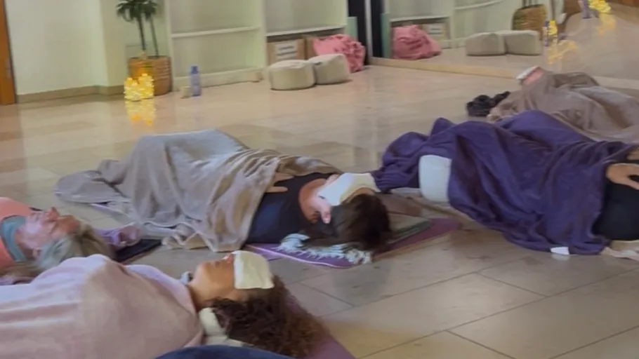 People relaxing on mats with eye masks indoors.