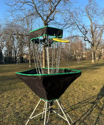 Disc golf basket with disc, in park.