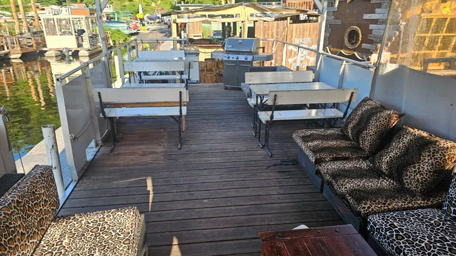 Holzterrasse mit Tischen und Leopardenmuster-Sofas.