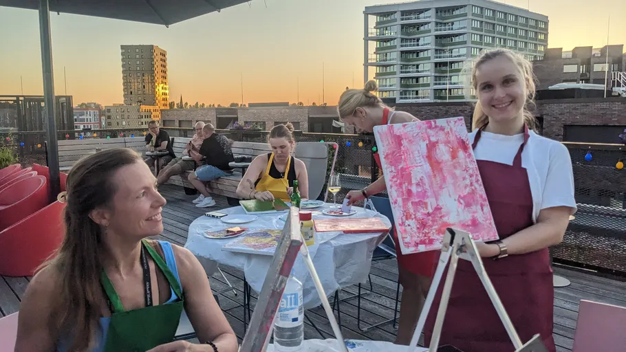 Women painting on rooftop at sunset.