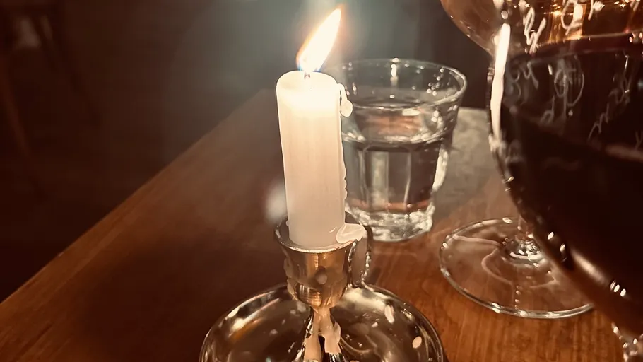 Kerze brennt, Weinglas in der Nähe.