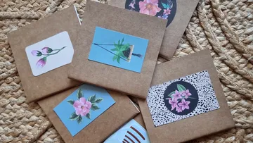 Bastelumschläge dekoriert mit Blumenaufklebern.