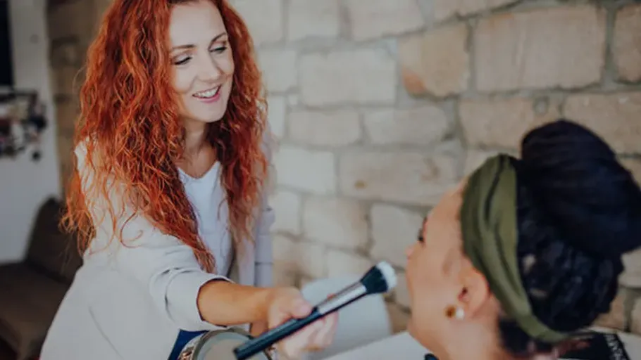 Woman applying makeup on another woman's face.