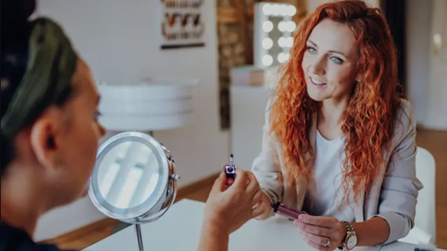 Two women discussing makeup in beauty salon.