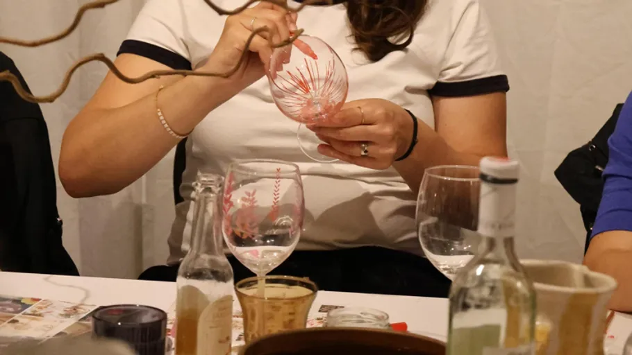 Person bemalt Weinglas am Tisch.