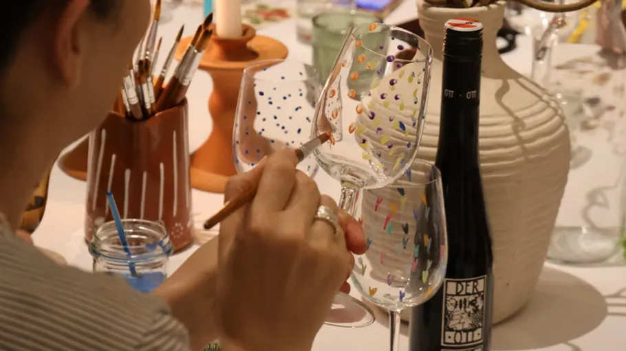 Person painting wine glasses at table.