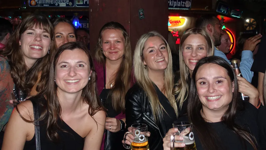 Group of women smiling with drinks in bar.
