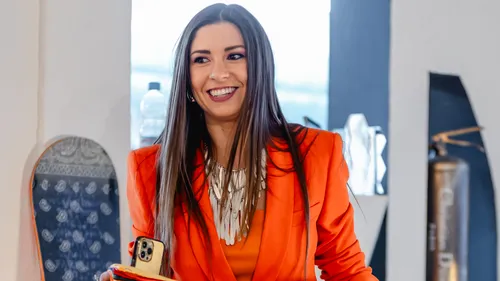Woman in orange suit smiling indoors.