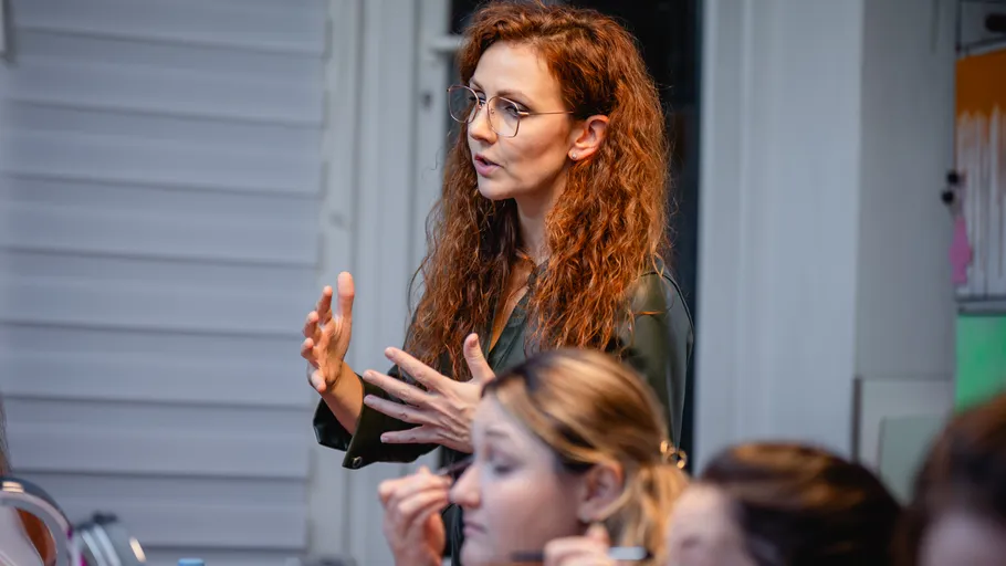 Frau gestikuliert beim Sprechen im Klassenzimmer.