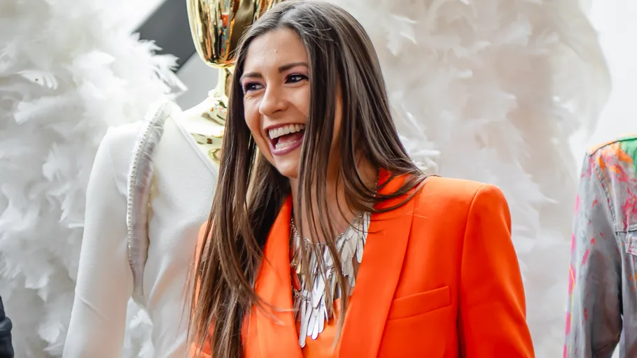 Smiling woman in orange suit at fashion event.