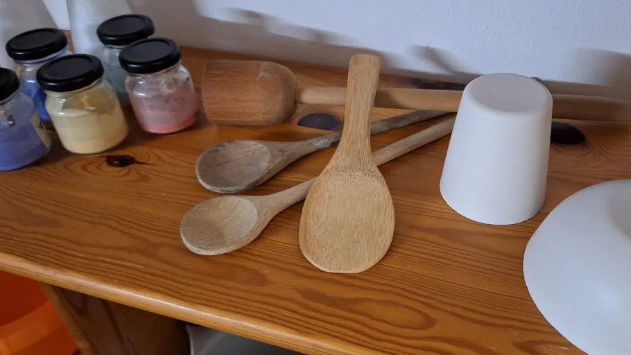 Wooden spoons and jars on wooden shelf.