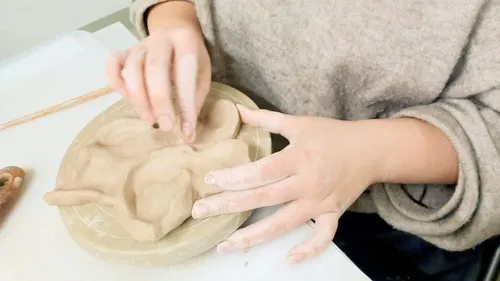 Woman sculpting clay on table indoors.