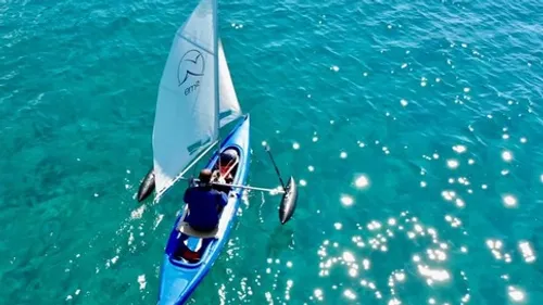 Man sailing kayak on clear blue water.
