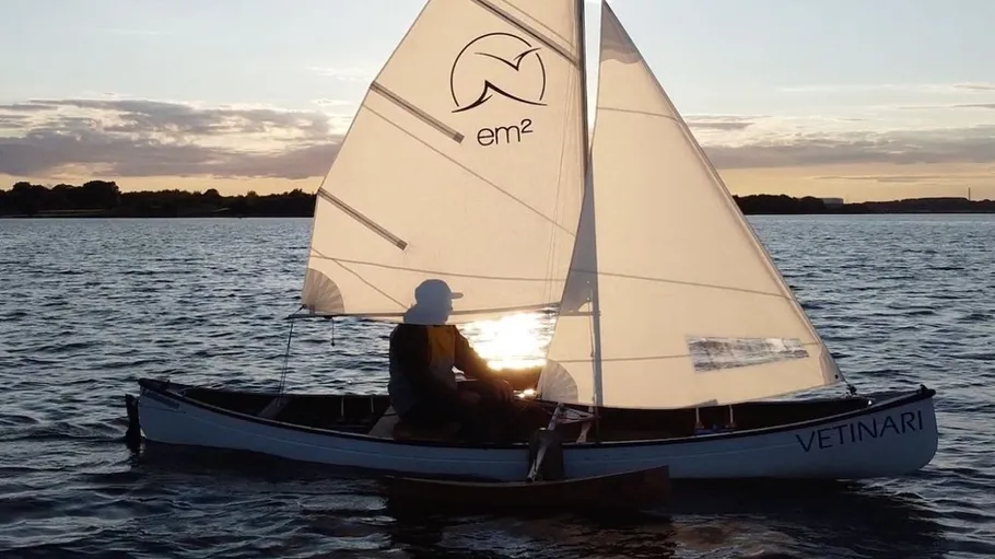 Person sailing small boat during sunset.