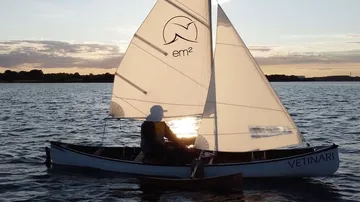 Sailboat on water at sunset, person sailing.