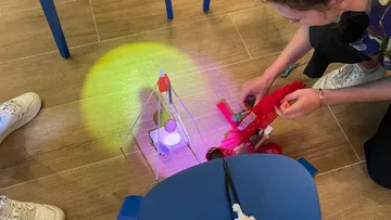 Person montiert Spielzeugroboter auf Holzboden.