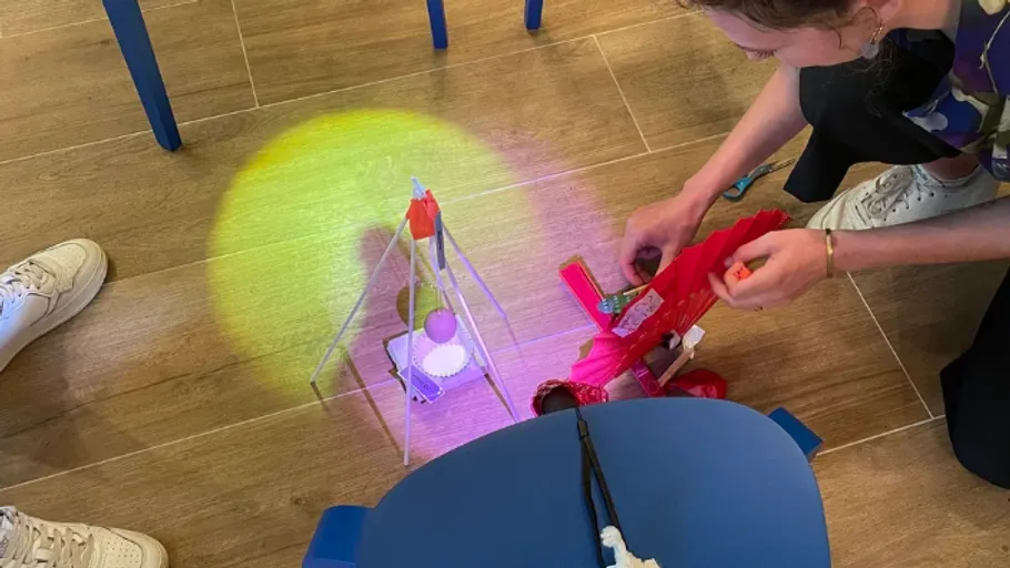 Person assembling toy robot on wooden floor.